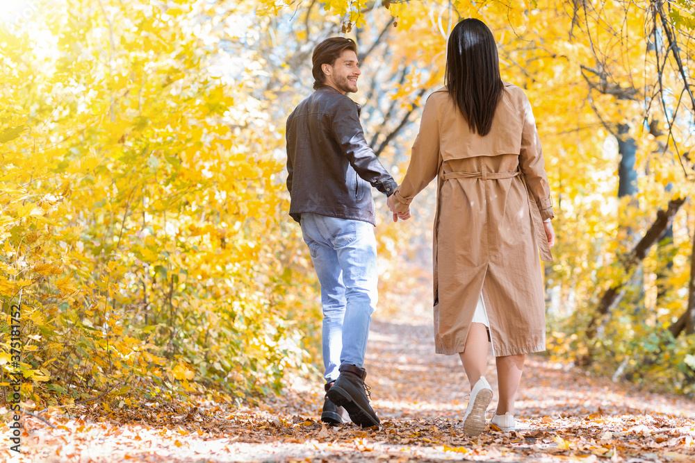 Fototapeta premium Excited man pulling his girlfriend while walking by forest