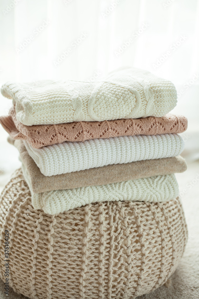 Knitted sweater. Women's sweaters lie on the ottoman. Cozy autumn clothes.