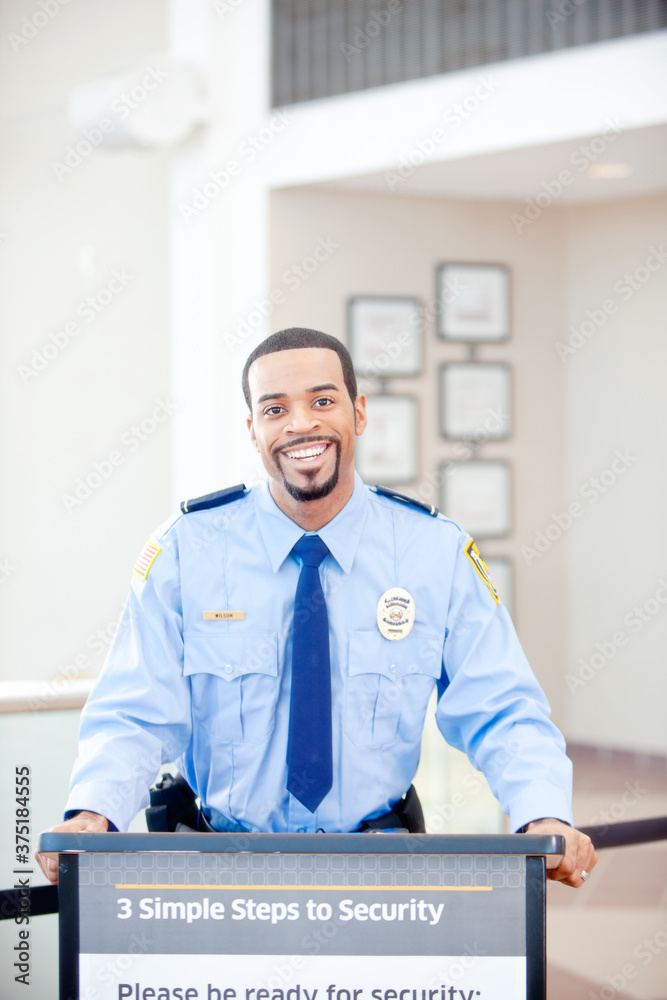 Airport: Cheerful Security Guard at Inspection Podium Airport: Cheerful Security Guard at Inspection Podium
