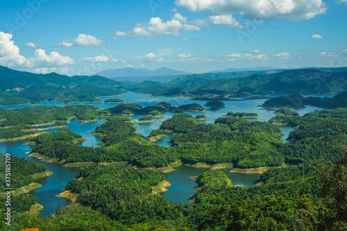 Fototapeta Naklejka Na Ścianę i Meble -  Ta Dung lake in the summer. Blue sky and cloudy on the lake and the trees on the small island paradise. Dak Nong global geological park, Dak Nong province, Vietnam.