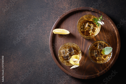 Three glasses of whiskey served on rocks on brown background. Copy space. View from above.