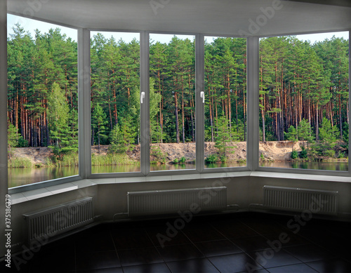window in modern room with panoramic view to forest lake © alexmak