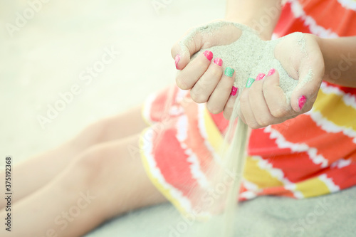 Sand slipping through a girls fingers at the beach photo