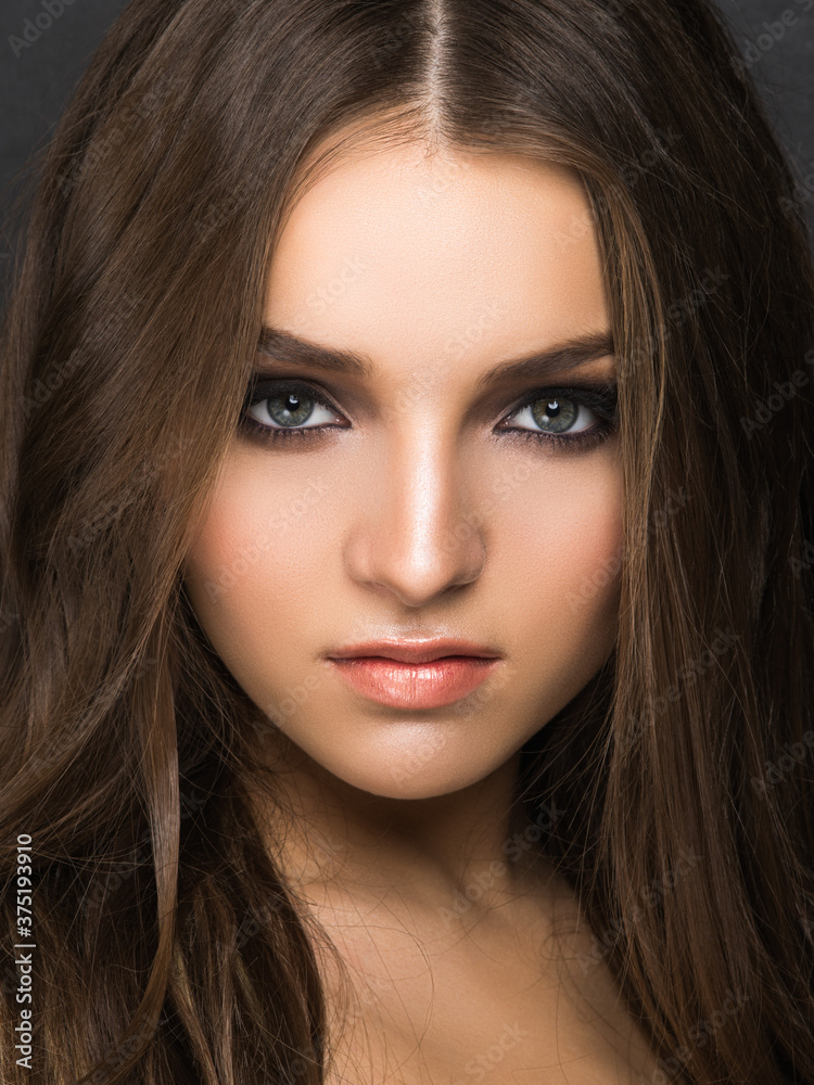 Fototapeta premium Young pretty female model with sophisticated makeup looking at camera isolated on black.