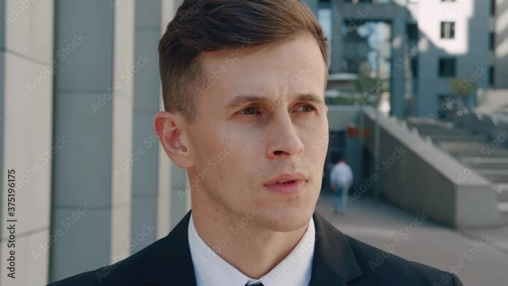 Portrait of attractive business man in business suit in looking into camera in the city on downtown district. Confident male businessman standing outdoor near office building. Portrait of attractive business man in business suit in looking into camera in the city on downtown district. Confident male businessman standing outdoor near office building.