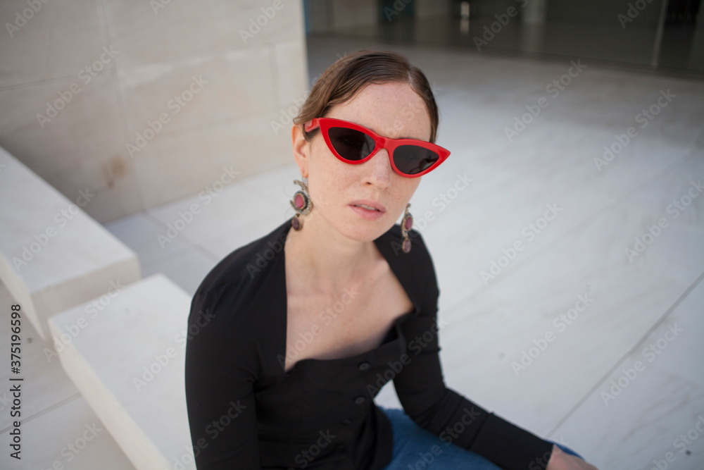 Outdoor portrait of young attractive woman, posing over grey wall.