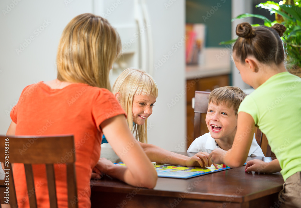 Mother plays board game with elementary aged children Mother plays board game with elementary aged children