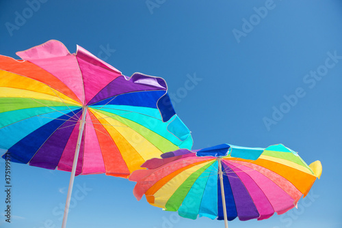 Colorful beach umbrellas against a blue summer sky photo