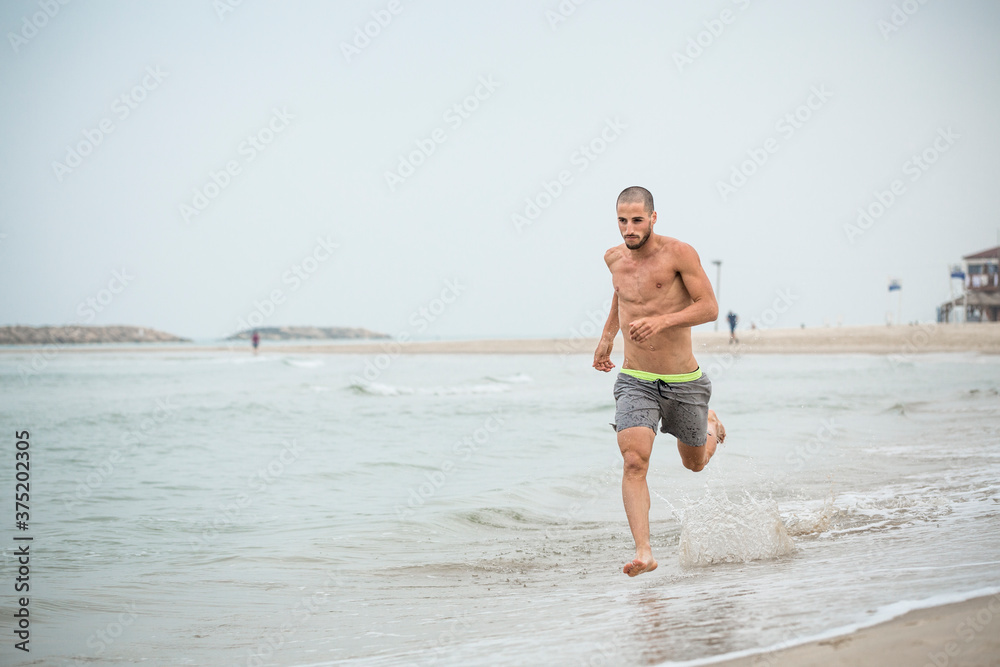 Young handsome athlete running in the beach Young handsome athlete running in the beach