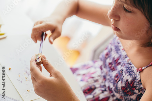 Young girl sharpening the pencil