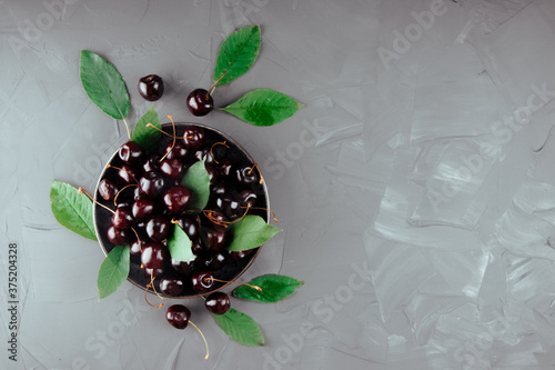 Ripe cherries on a plate and concrete background, top view, free space for text photo