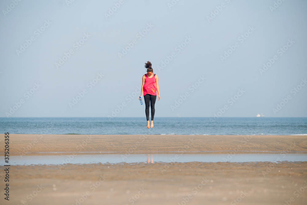 Healthy young woman jumping on the beach during her workout. Healthy young woman jumping on the beach during her workout.