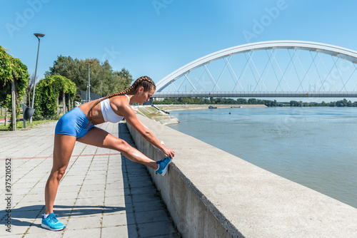 Young sexy strong muscular fit sweaty woman stretching her muscles after hard outdoor cross workout training © Srdjan