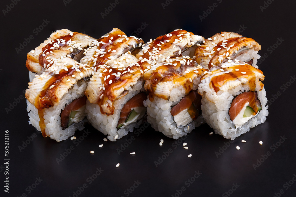 Traditional delicious fresh Unagi Syake sushi roll set on a black background with reflection.