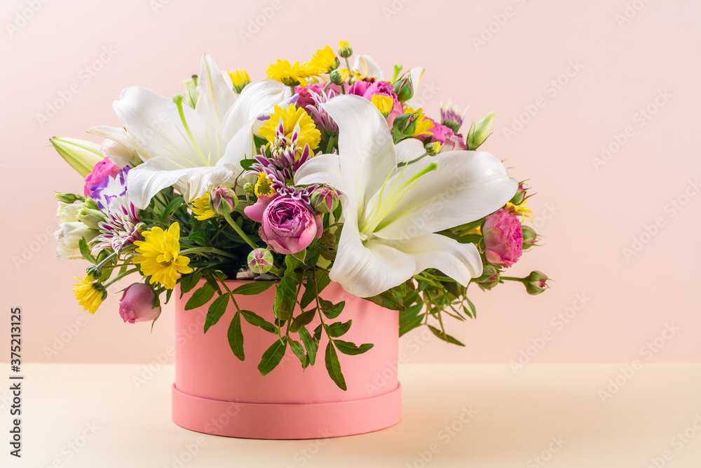 Beautiful buch of flowers in pink box on peach and almond oil color background. Beautiful buch of flowers in pink box on peach and almond oil color background.