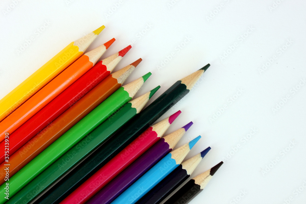 Colored pencils on a white background. Lots of different colored pencils. Colored pencil. Pencils are sharp. Pencils lie diagonally in the lower left corner. Close-up. Copy space. Background. Flat lay