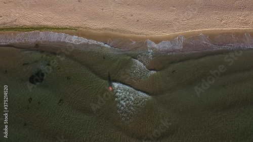 A man walks on the beach by the sea, aerial shot