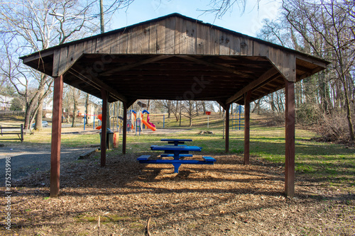 A Wooden Gazebo in a Park in the Suburbs With Picnic Tables Underneath