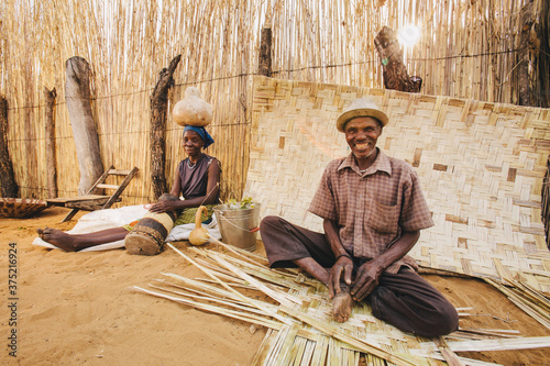 Namibian Hambukush man and woman weaving outside their kraal