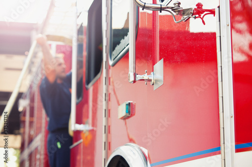 Firehouse: Fire Fighter Putting Hose Back On Truck photo