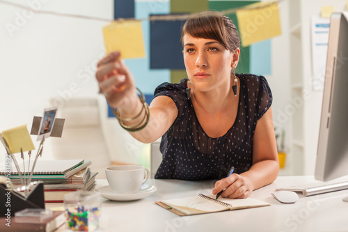 Woman Writing Reminders on Post Its photo