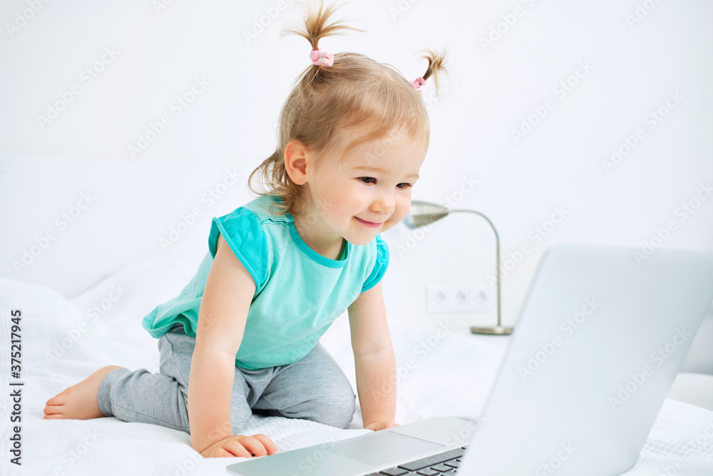 Caucasian kid sitting on bed and watching cartoons in laptop Caucasian kid sitting on bed and watching cartoons in laptop