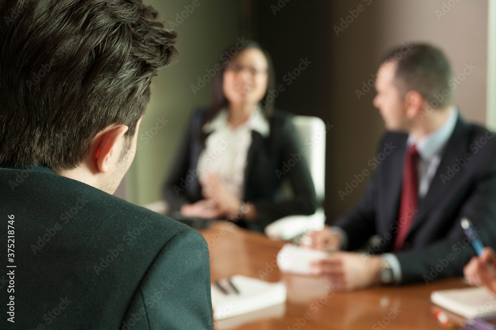 Looking over the shoulder of a young executive to two colleagues Looking over the shoulder of a young executive to two colleagues