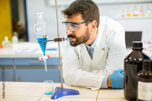 Researcher working with blue liquid at separatory funnel photo