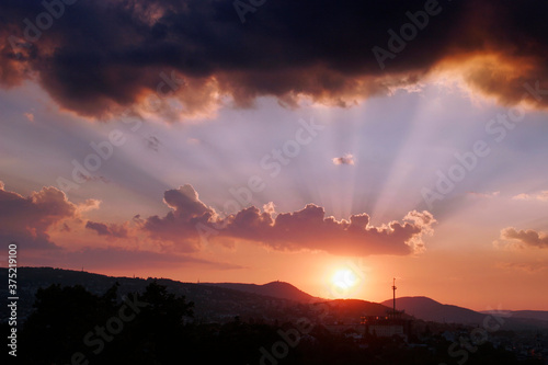Setting sun with twighlight rays above hills
