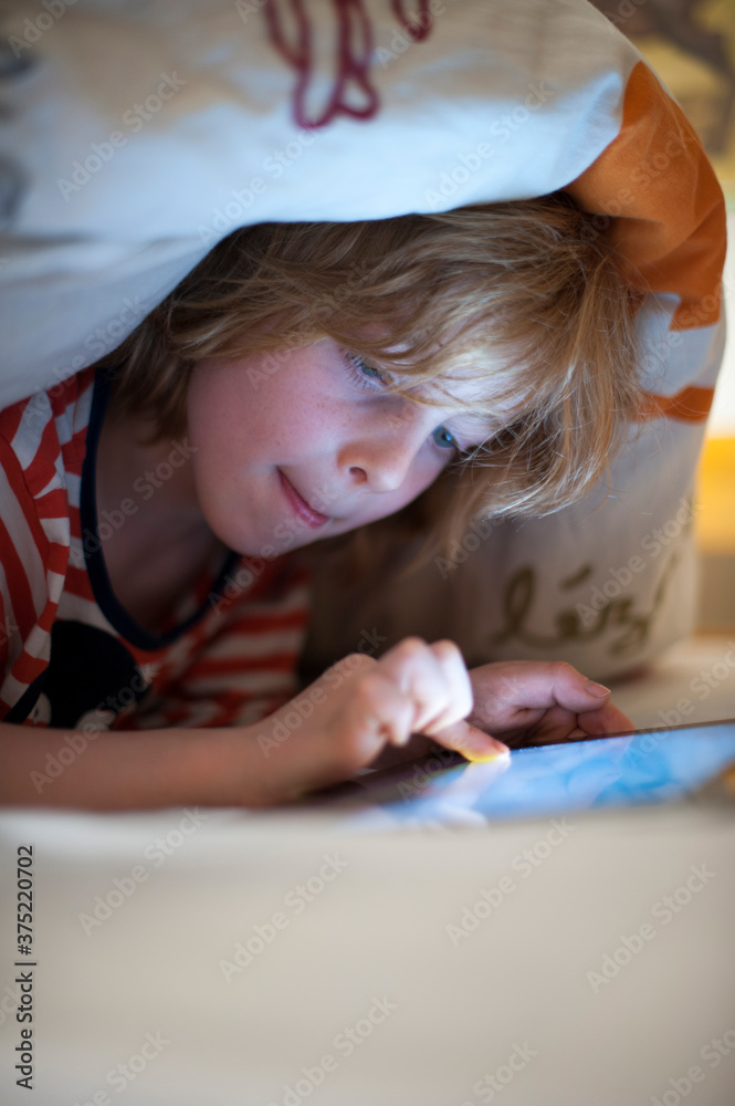 boy using a digital tablet in bed boy using a digital tablet in bed