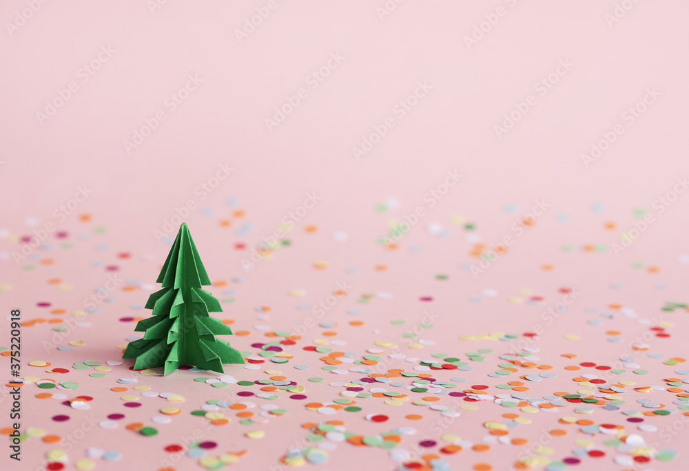 Christmas composition with paper fir-tree and multicolored confetti. Christmas origami fir trees with copy space for text. New Year's minimal concept. Christmas composition with paper fir-tree and multicolored confetti. Christmas origami fir trees with copy space for text. New Year's minimal concept.