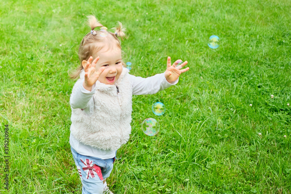 Caucasian toddler running in the park for soap bubbles Caucasian toddler running in the park for soap bubbles