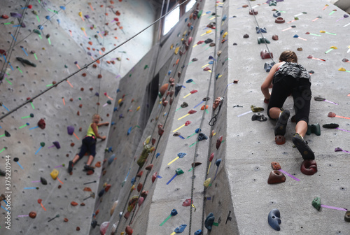 Two young girls determined to get to the top of the rock wall