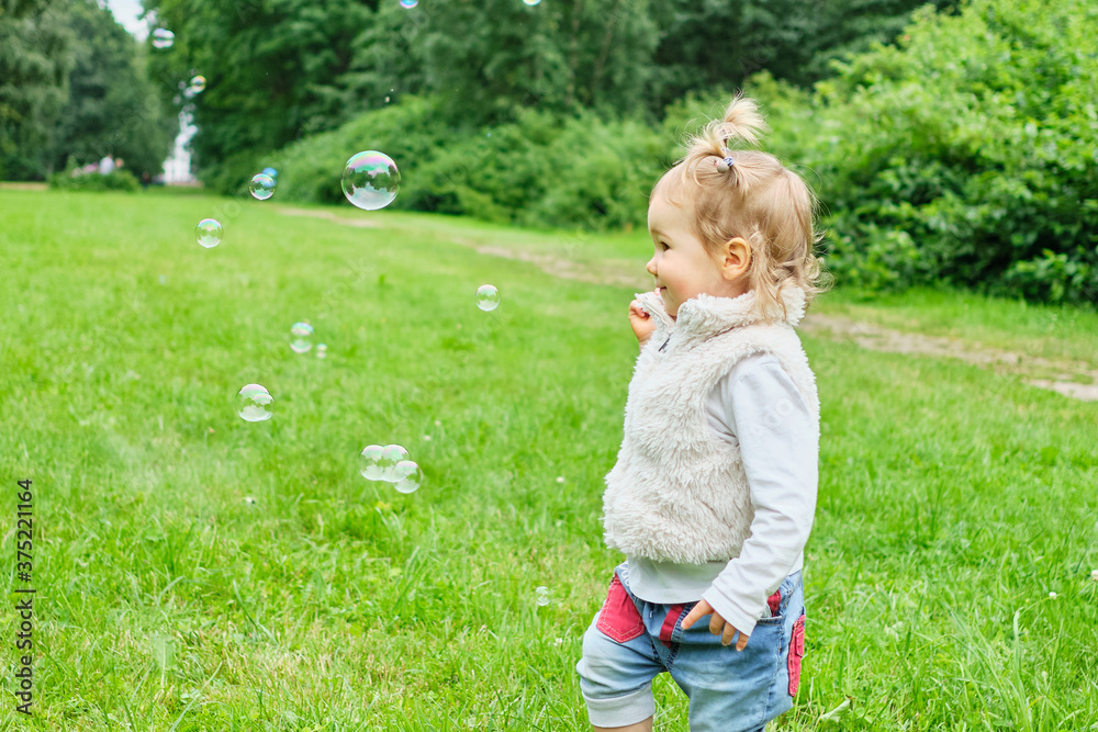 Caucasian toddler running for soap bubbles in summer time Caucasian toddler running for soap bubbles in summer time