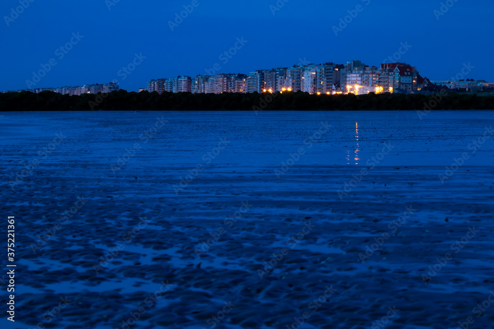 Town at blue hour on a beach on the Belgian coast on a summer night.