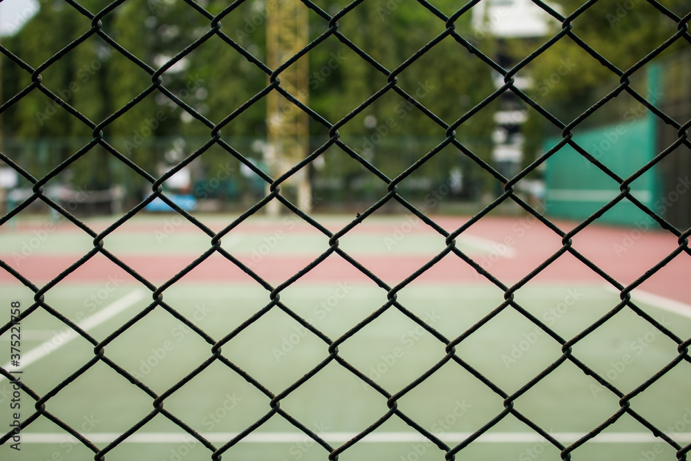 Fototapeta premium Close up the metal fence in front of a tennis court on the field