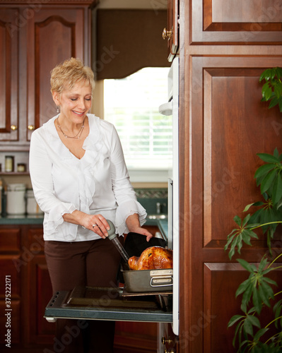 Thanksgiving: Grandmother Helps to Baste Turkey photo