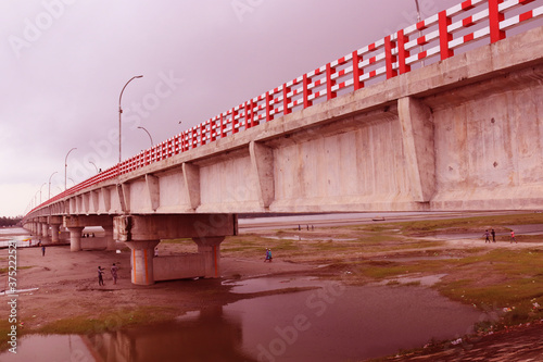 Long Big concrete bridge.An elevated concrete highway spanning across a Dark cloudy sky.view under the grey briage in the city.Modern construction engineering for road. photo