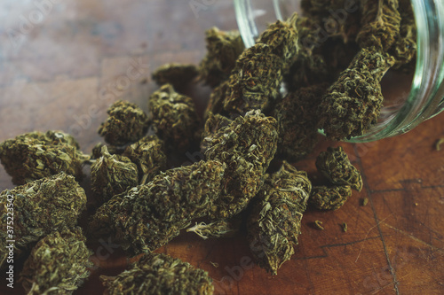 Dried Cannabis with jar and wood background   photo