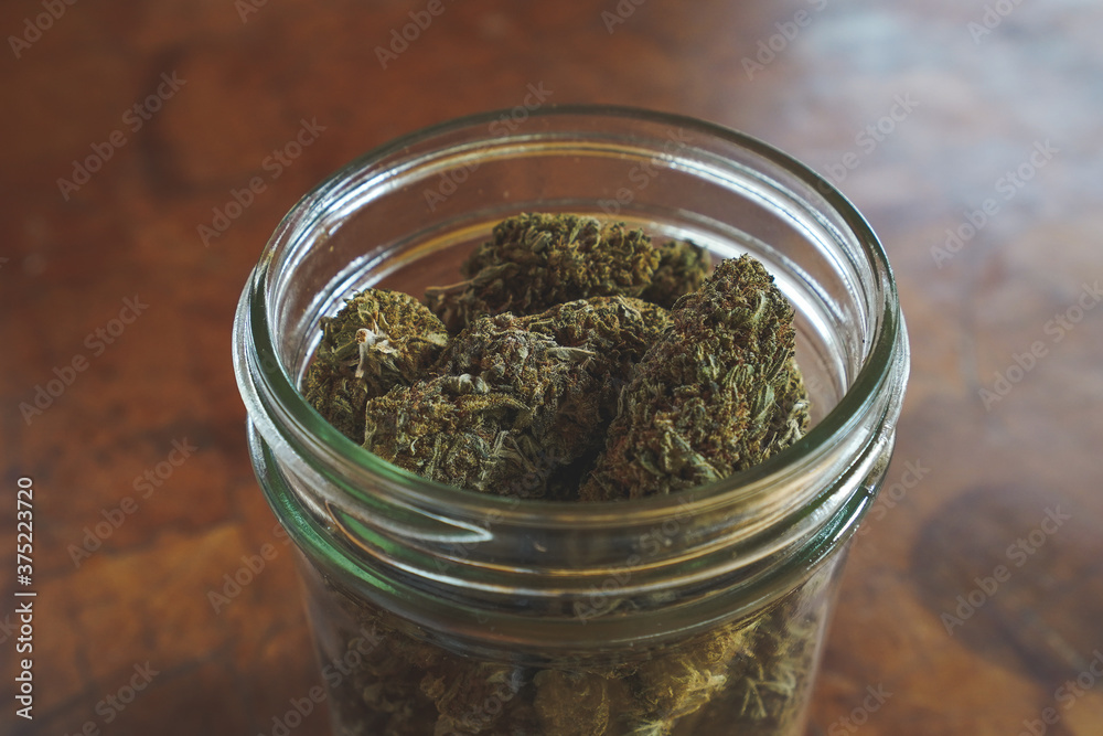 Dried Cannabis with jar and wood background Dried Cannabis with jar and wood background