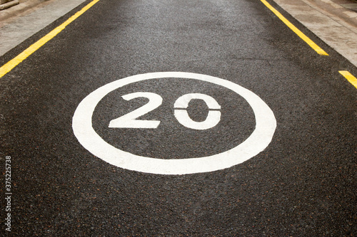 Speed limit sign 20 on the road close up. Traffic sign 20 on a blurred background road. Road sign 20 on wet asphalt road. Call for speed reduction © New Happy World