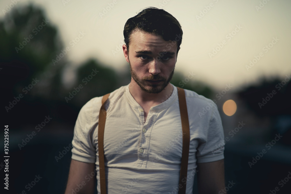 A handsome young man stands outside at twilight A handsome young man stands outside at twilight