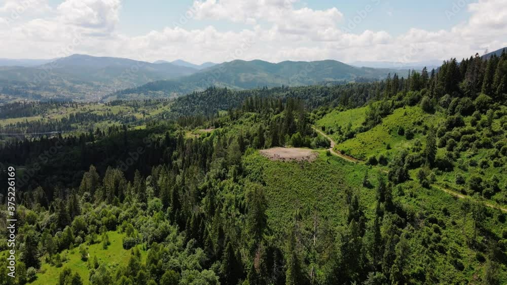 Aerial view of mountain gorge hills covered by green forest. Drone camera pan and flies over mountain settlement, beautiful hilly landscape sunny weather Aerial view of mountain gorge hills covered by green forest. Drone camera pan and flies over mountain settlement, beautiful hilly landscape sunny weather
