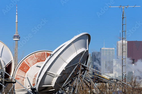 Collection of satellite dishes and antenae with Toronto highrise skyline photo