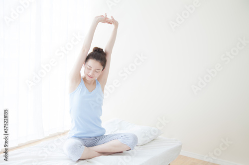 ベッドの上でストレッチをする女性