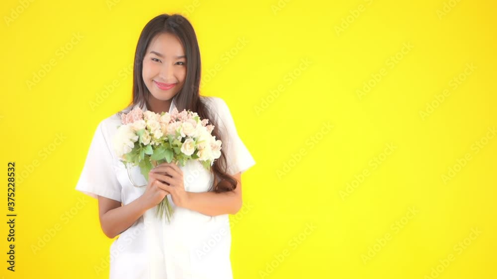 Asian female healthcare doctor offering bouquet flowers. Copy Space. Isolated yellow background Asian female healthcare doctor offering bouquet flowers. Copy Space. Isolated yellow background
