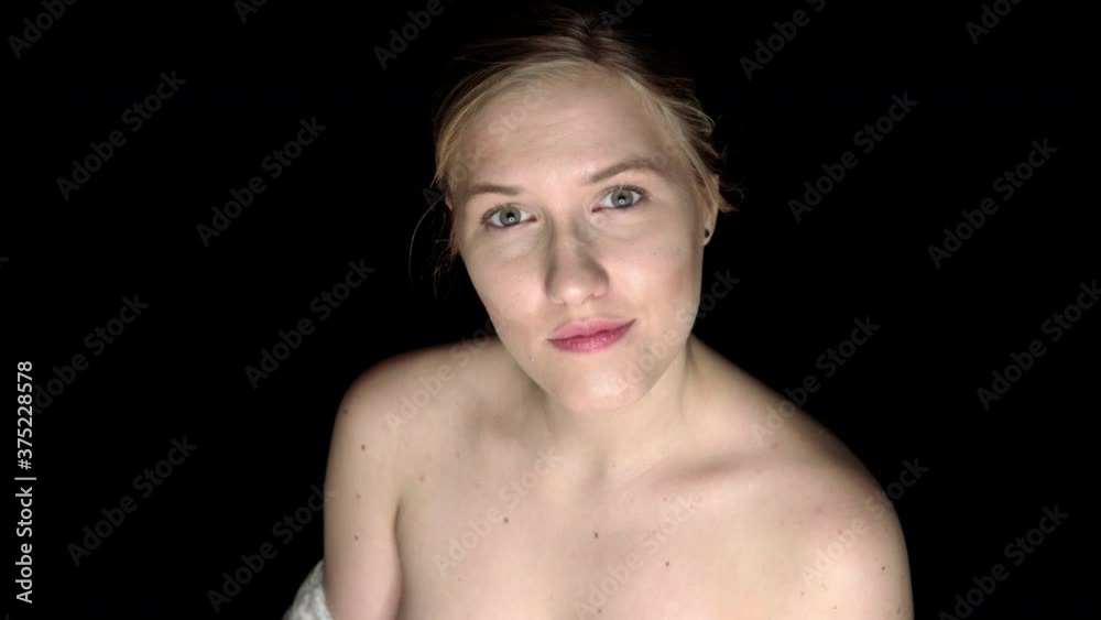 Young blond woman is standing on black background and looking on camera. Head and shoulders shot. She looks sexy and sensual. Young blond woman is standing on black background and looking on camera. Head and shoulders shot. She looks sexy and sensual.
