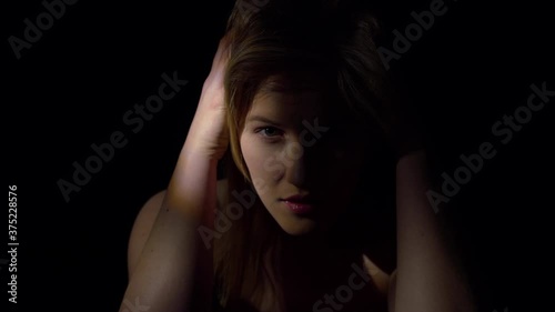 Seductive woman. The face of a smiling woman in twilight on a black background. The eyes and mouth are visible. Concept of sexuality and desire. photo