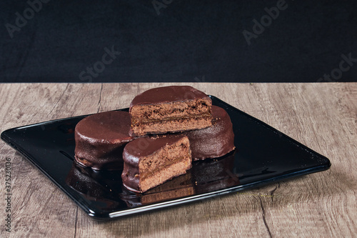 Foto Chocolate alfajor on black plate on a wooden table and dark background