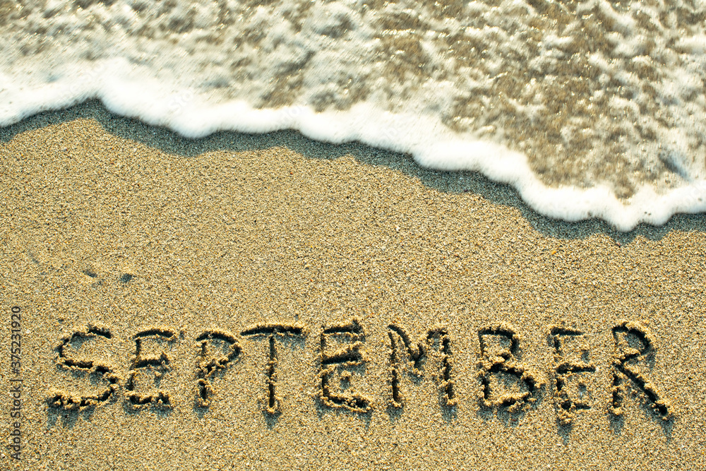 Fototapeta premium September inscription on the sand beach with the soft wave.